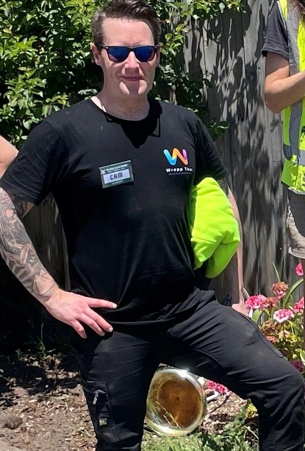 Man wearing sunglasses and a black T-shirt with a name tag that says Cam.